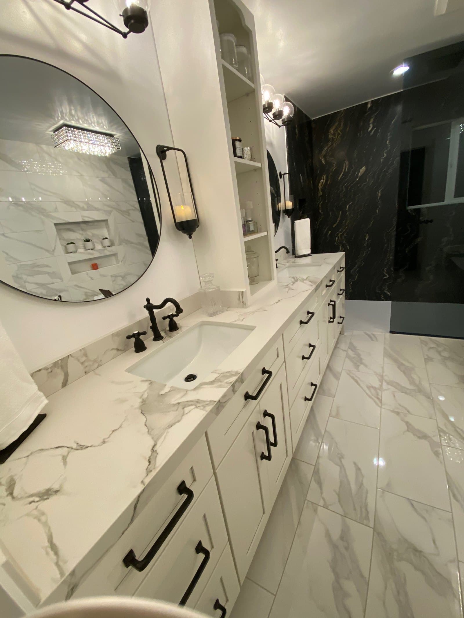 Double vanity with waterfall-edge Calacatta marble countertop and black granite feature wall