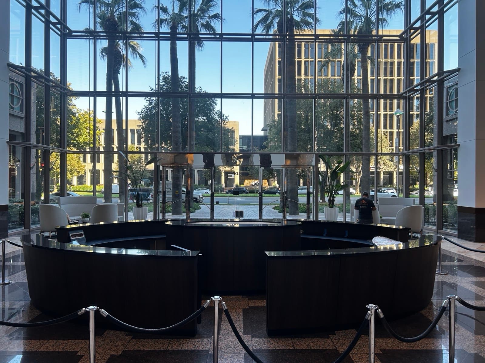 Circular lobby reception desk with polished black stone countertops in a glass atrium